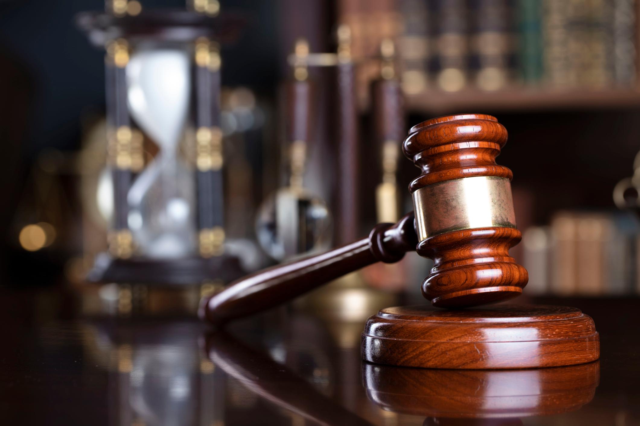 Gavel and scale on the judge desk. Book shelf in the background.